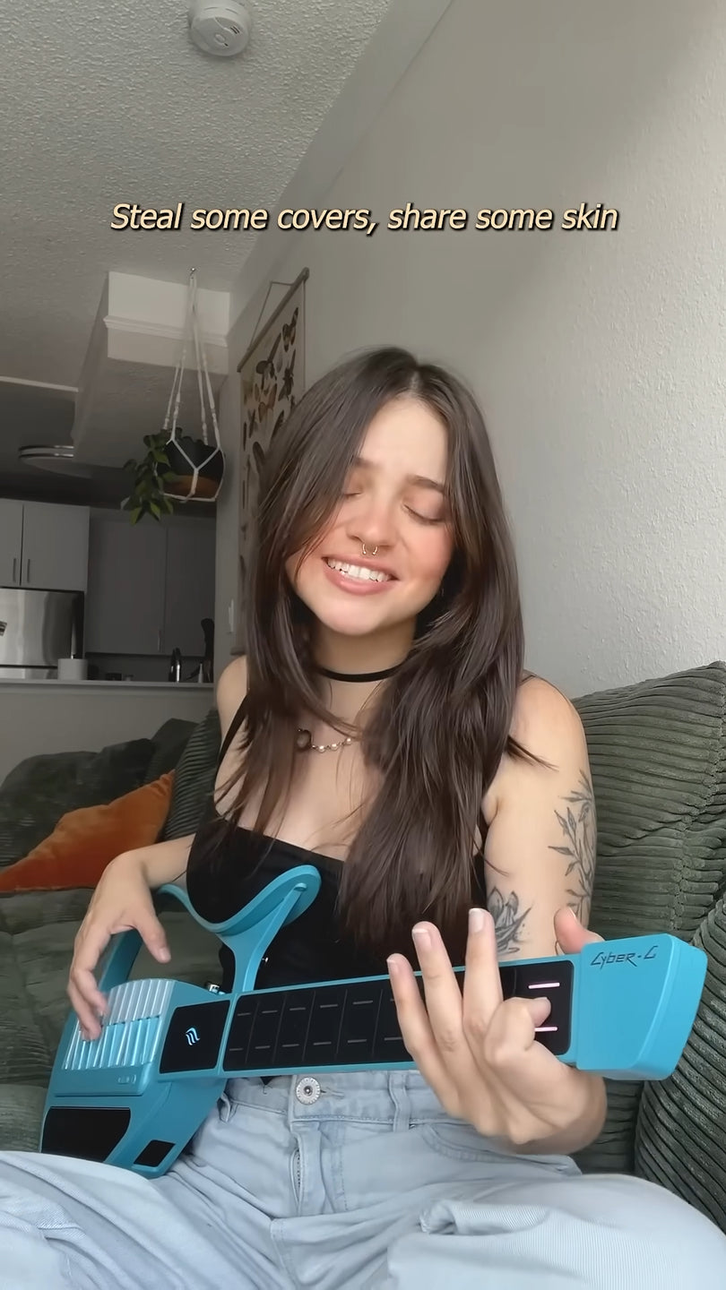 Woman holding a Cyber-G guitar with text in a casual indoor setting.