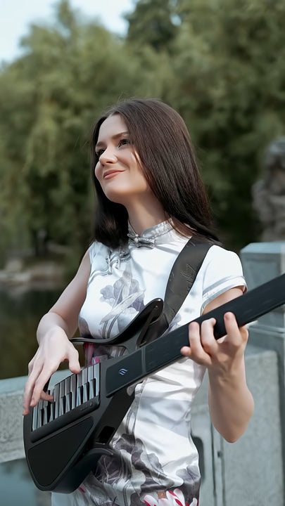Woman holding a Cyber-G guitar outdoors with greenery in the background