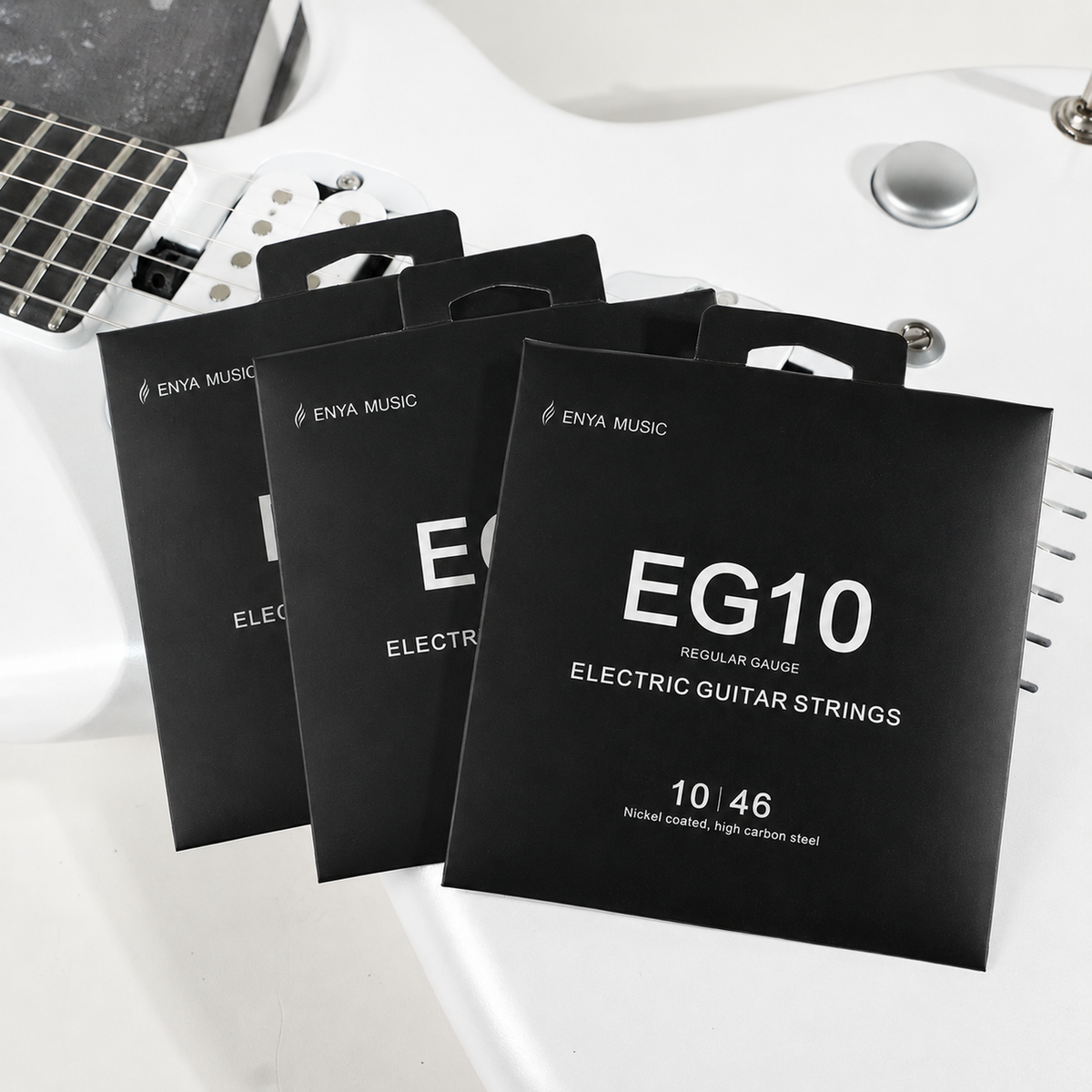 3 packages of Enya Music electric guitar strings on a white surface with a guitar in the background.