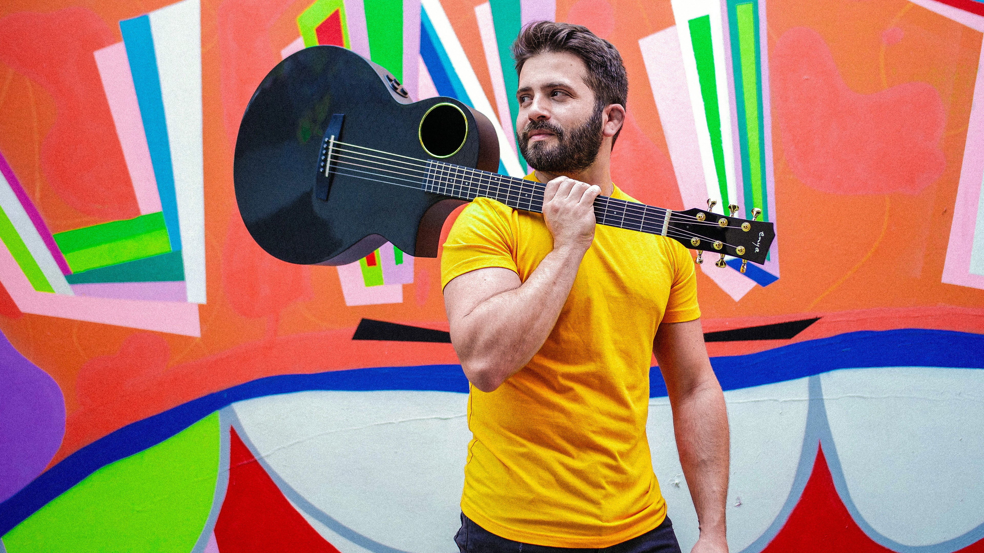 Guitarist Luca standing in front of a colorful wall, his X4 pro carrying on his shoulders.