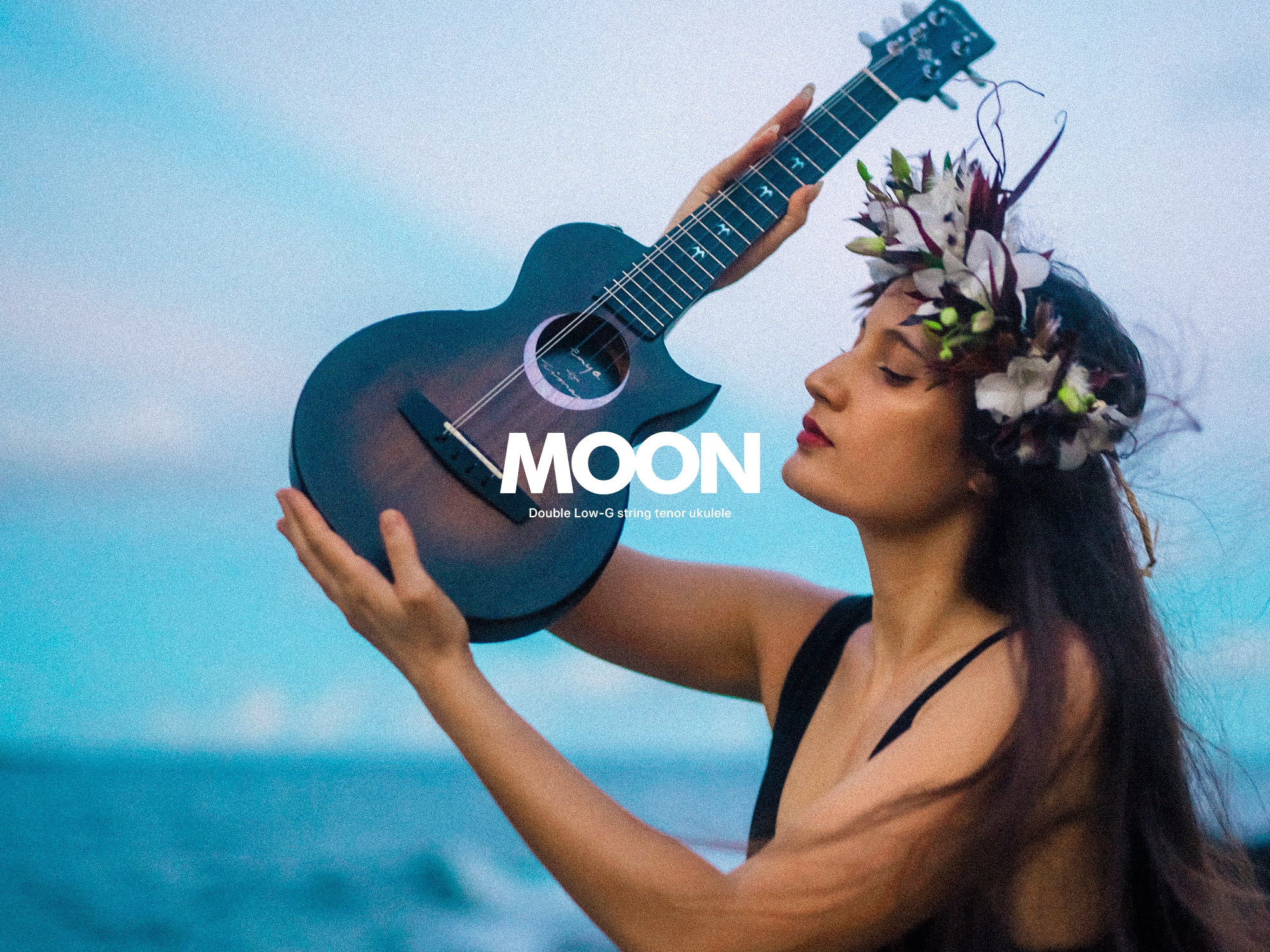 Artist Taimane lifting her signature 5-string Ukulele into the air next to the beach.