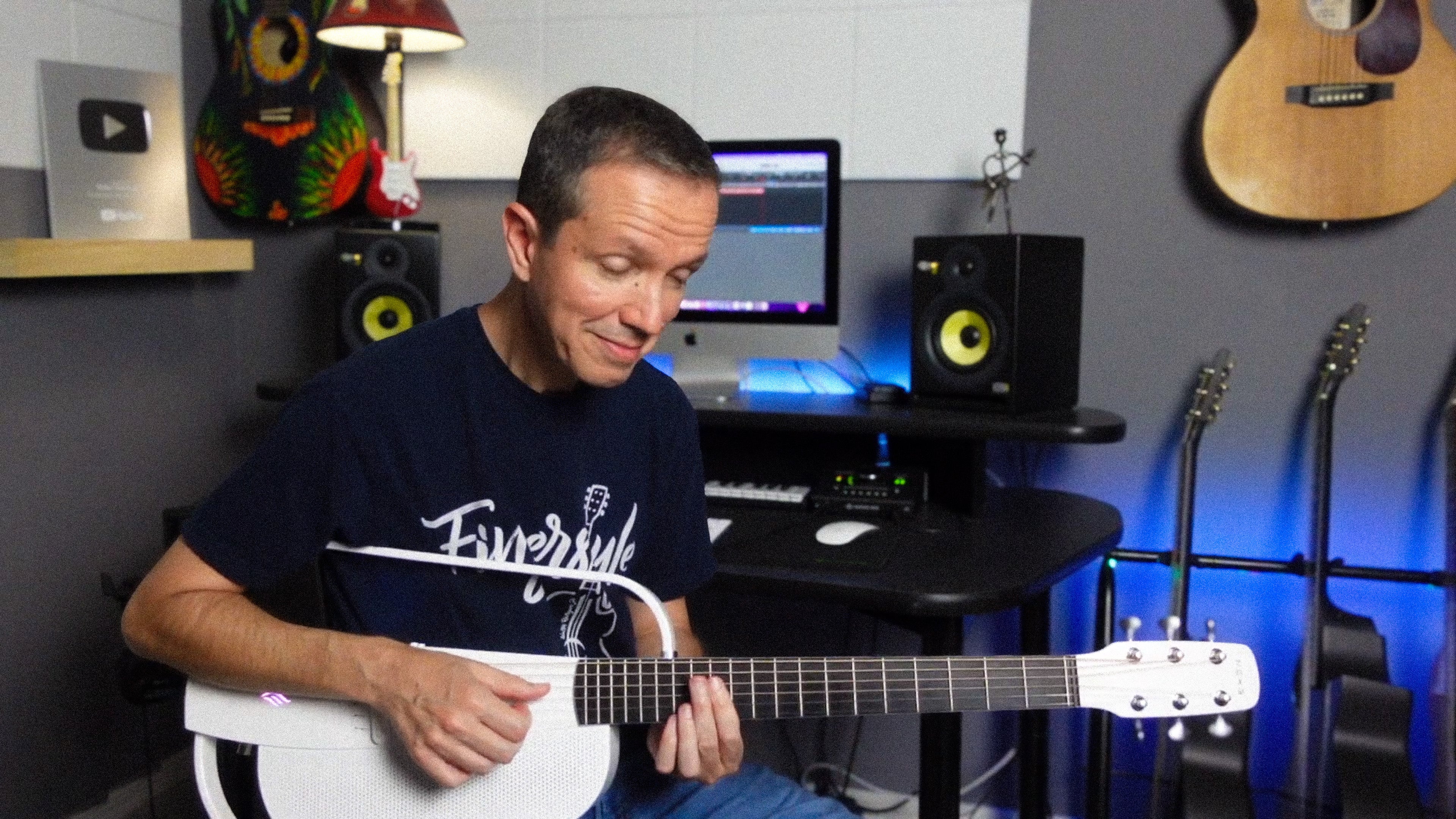 Guitarist Walter sitting and playing a white ENYA NEXG 2, closing his eyes, looks very enjoy.