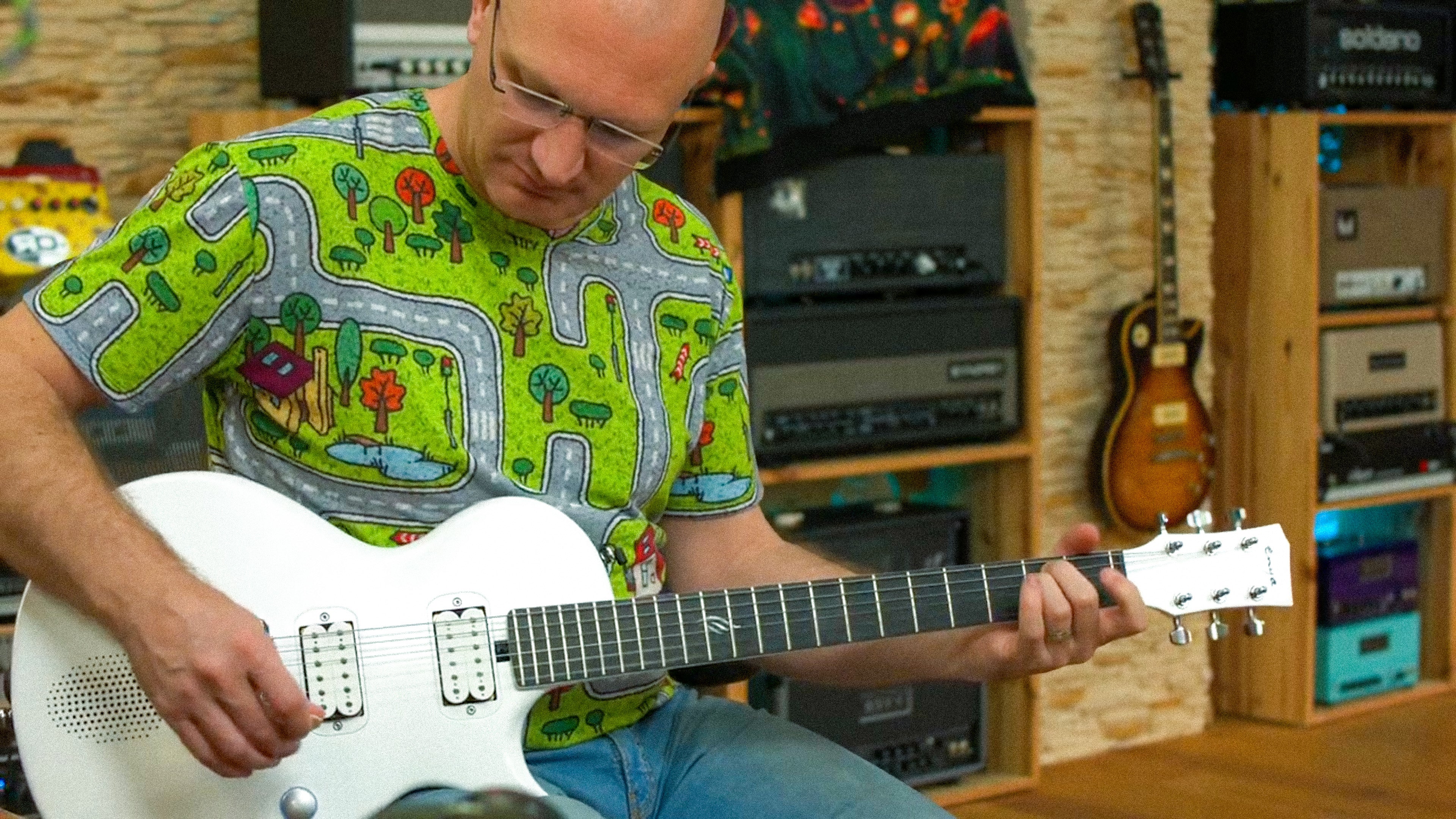 Henning sitting on the chair and playing a pearl white Nova Go Sonic.