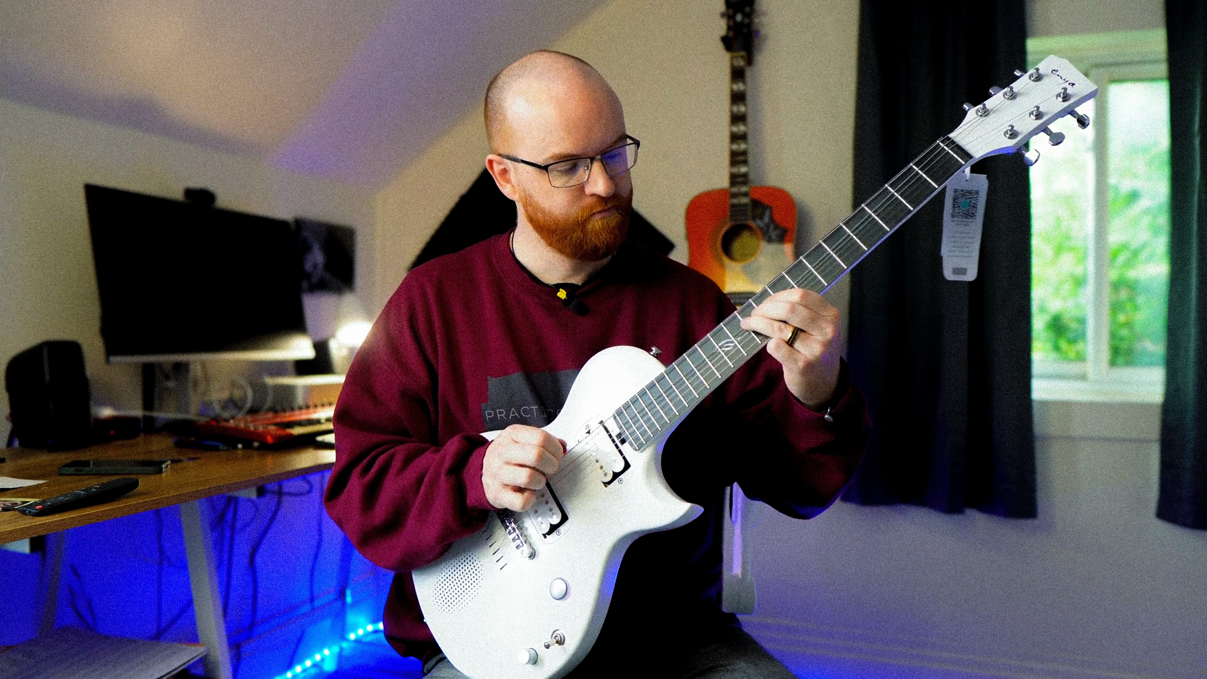 Jamie sitting on the chair and playing a pearl white Nova Go Sonic.