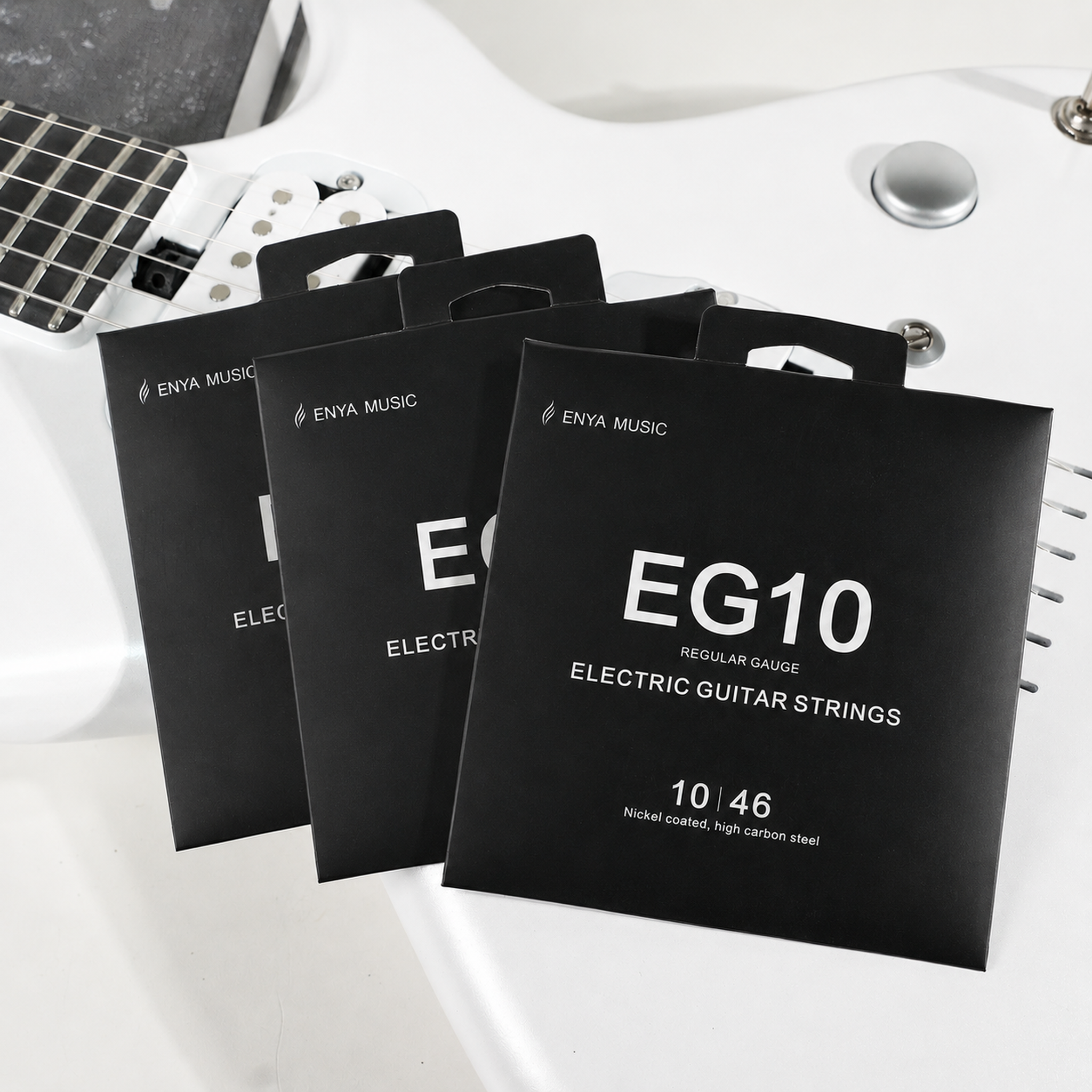 3 packages of Enya Music electric guitar strings on a white surface with a guitar in the background.