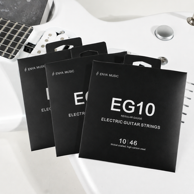 3 packages of Enya Music electric guitar strings on a white surface with a guitar in the background.