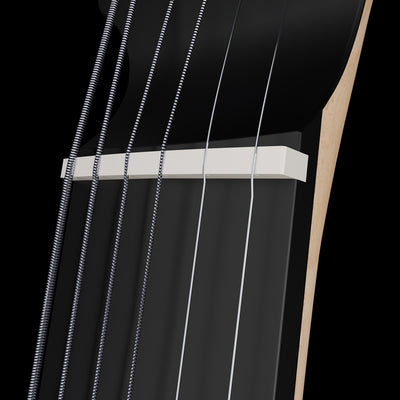 Close-up of a guitar's bone nut and strings on a black background